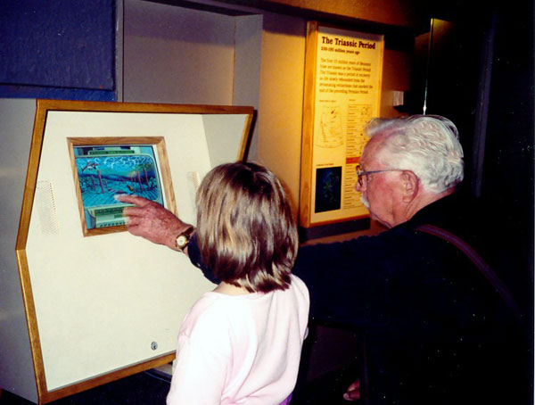 Jade and her grandfather learn about dinosaurs on an interactive video.  Photo by M. Maxine George