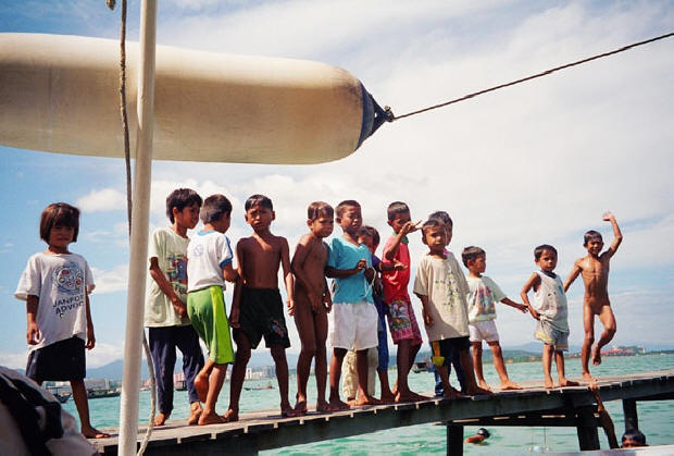 Malaysian children line dock to wave goodbye to visitors.