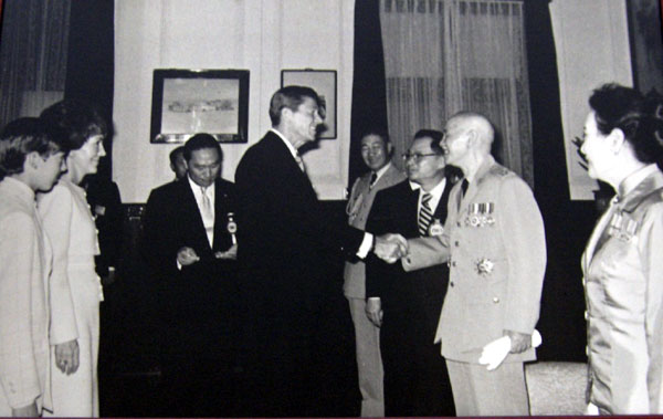 President Ronald Reagan and President Chiang Kai Shek shake hands while their wives look on.
