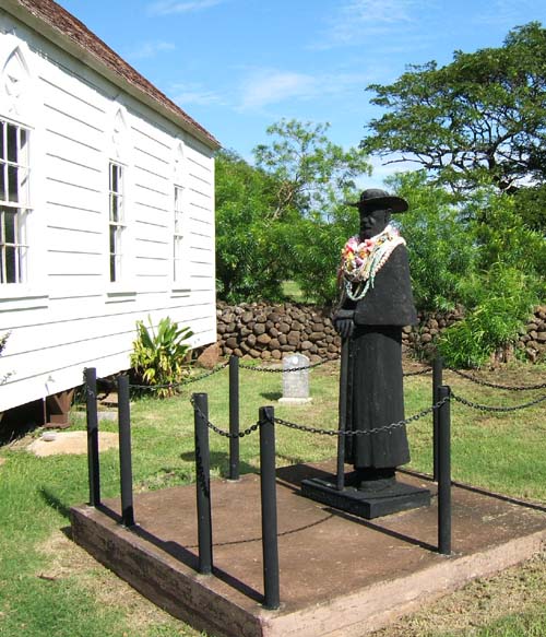 Statue of Father Damien alongside St. Joseph's Church is adorned with floral garlands