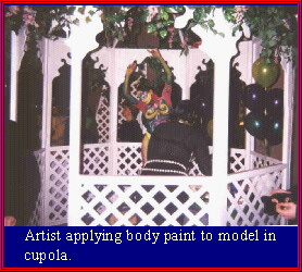 Artist applying body paint to model in cupola.